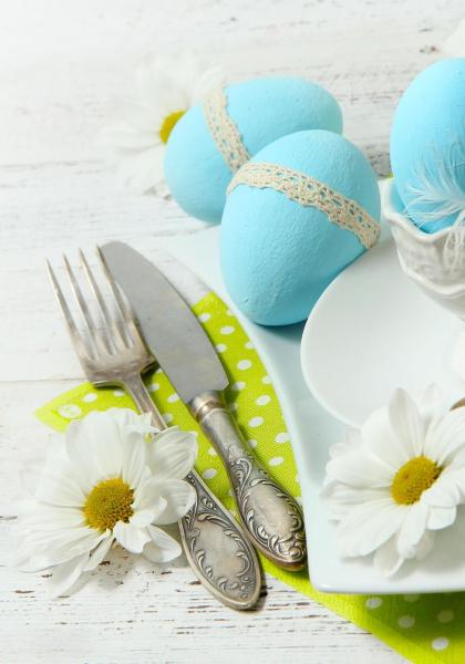 Œufs bleus décorés sur table printanière avec marguerites.