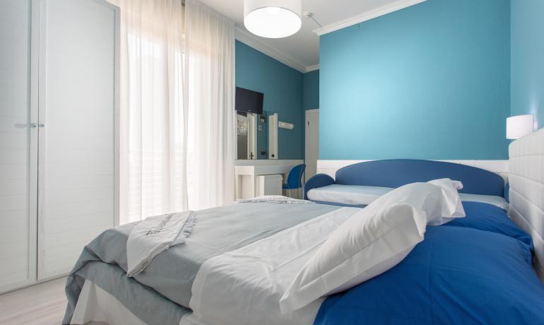 Chambre moderne avec murs bleus et meubles blancs.