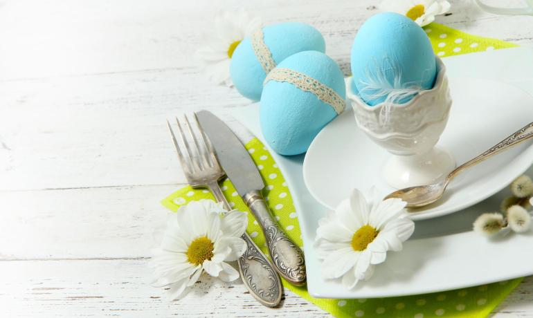 Œufs bleus décorés sur table printanière avec marguerites.